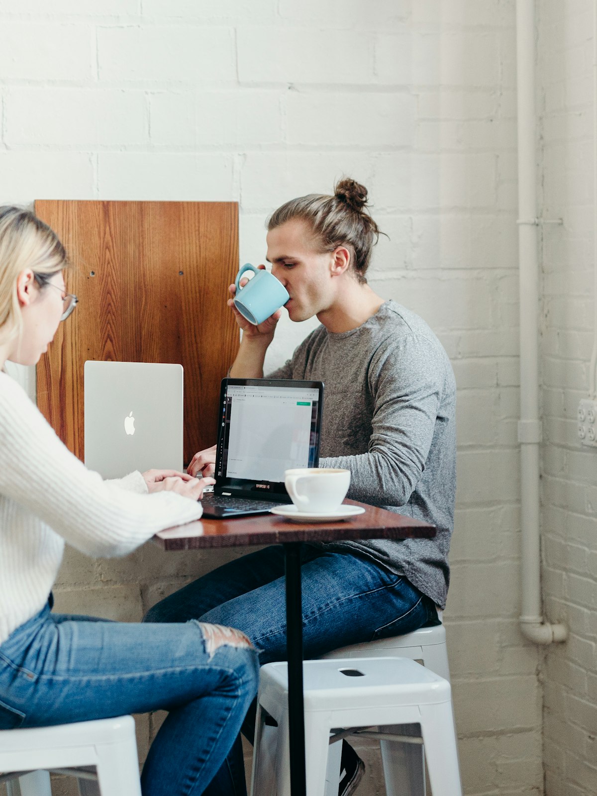Two people working across a small cafe table over coffee.